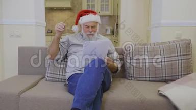 戴着圣诞老人帽的老人在家沙发上读<strong>心愿</strong>单